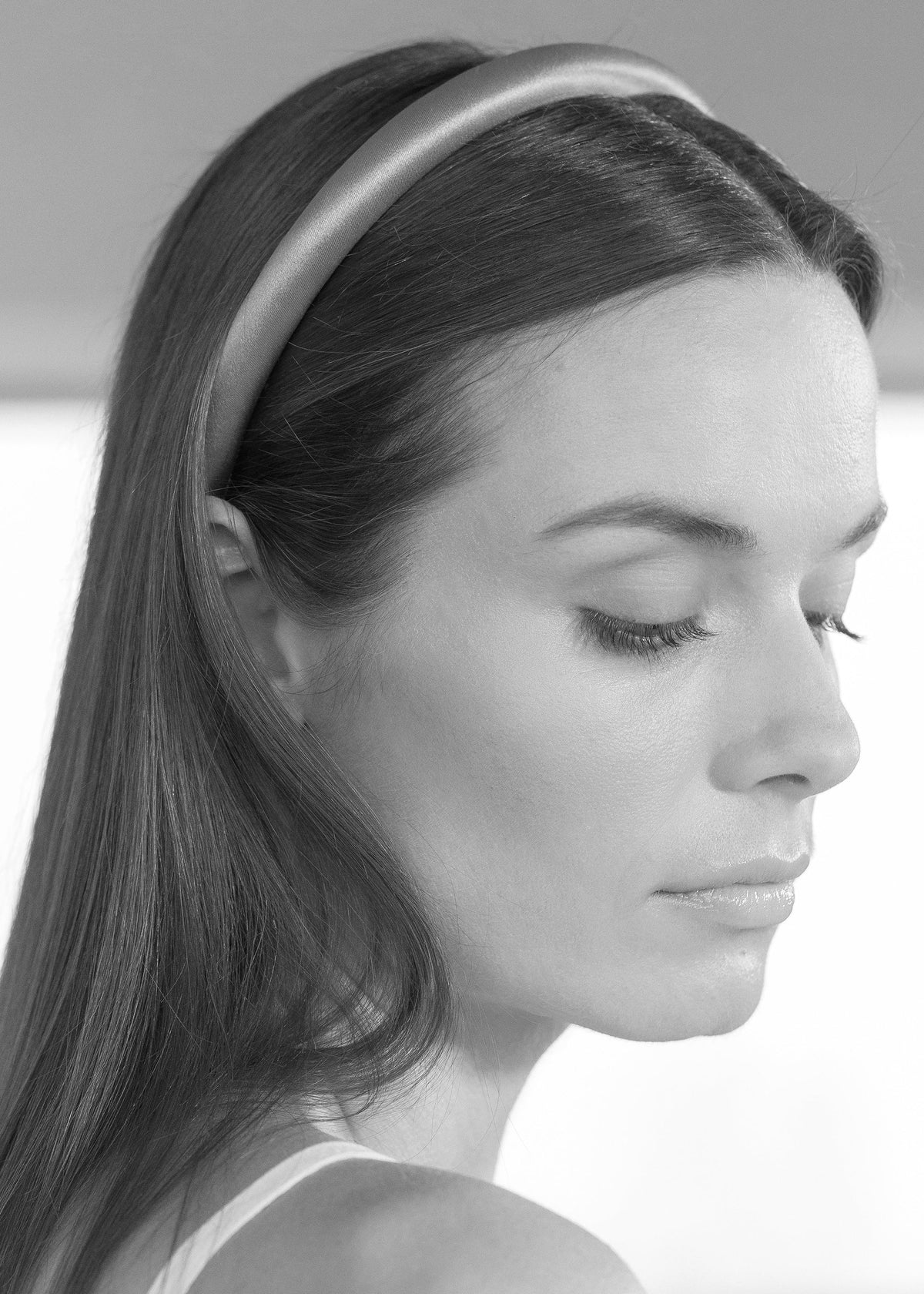 Close-up side view of Tiana Headband showcasing its padded silk shape on a model against a light background