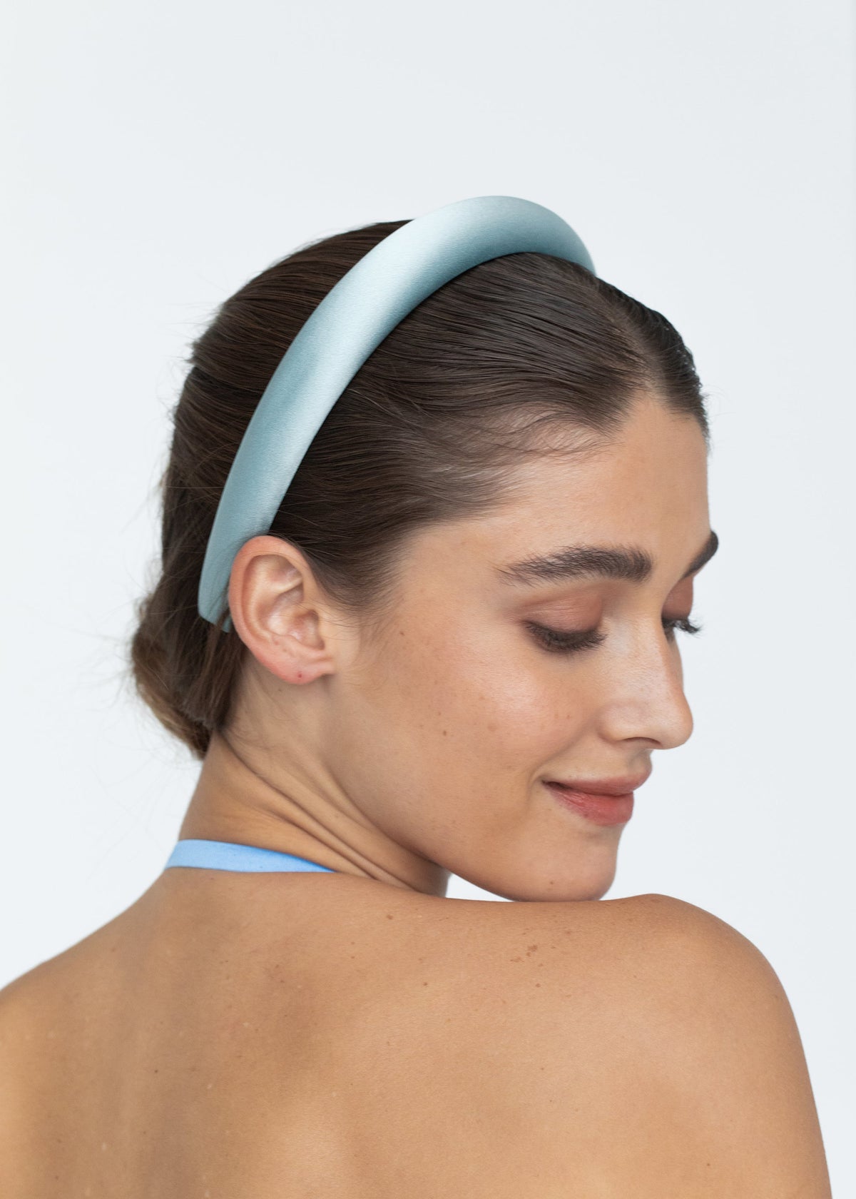 Close-up view of the Tori Headband in Satin in Powder showcasing its padded silk band worn by a model against a light background