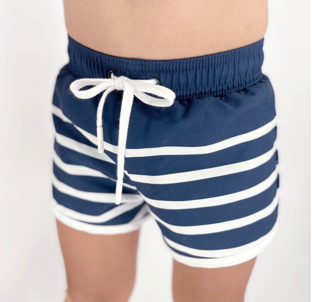 Front view of Boys Navy Breton Stripe Boardie with white drawstring, elastic waistband, and horizontal stripes on a model