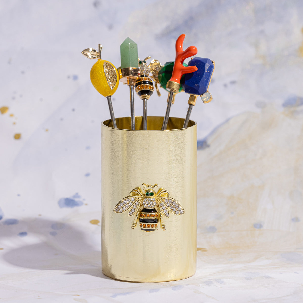 Front view of Stripey Small Bee Pot showcasing its jeweled bee embellishment and decorative picks with a white tabletop background