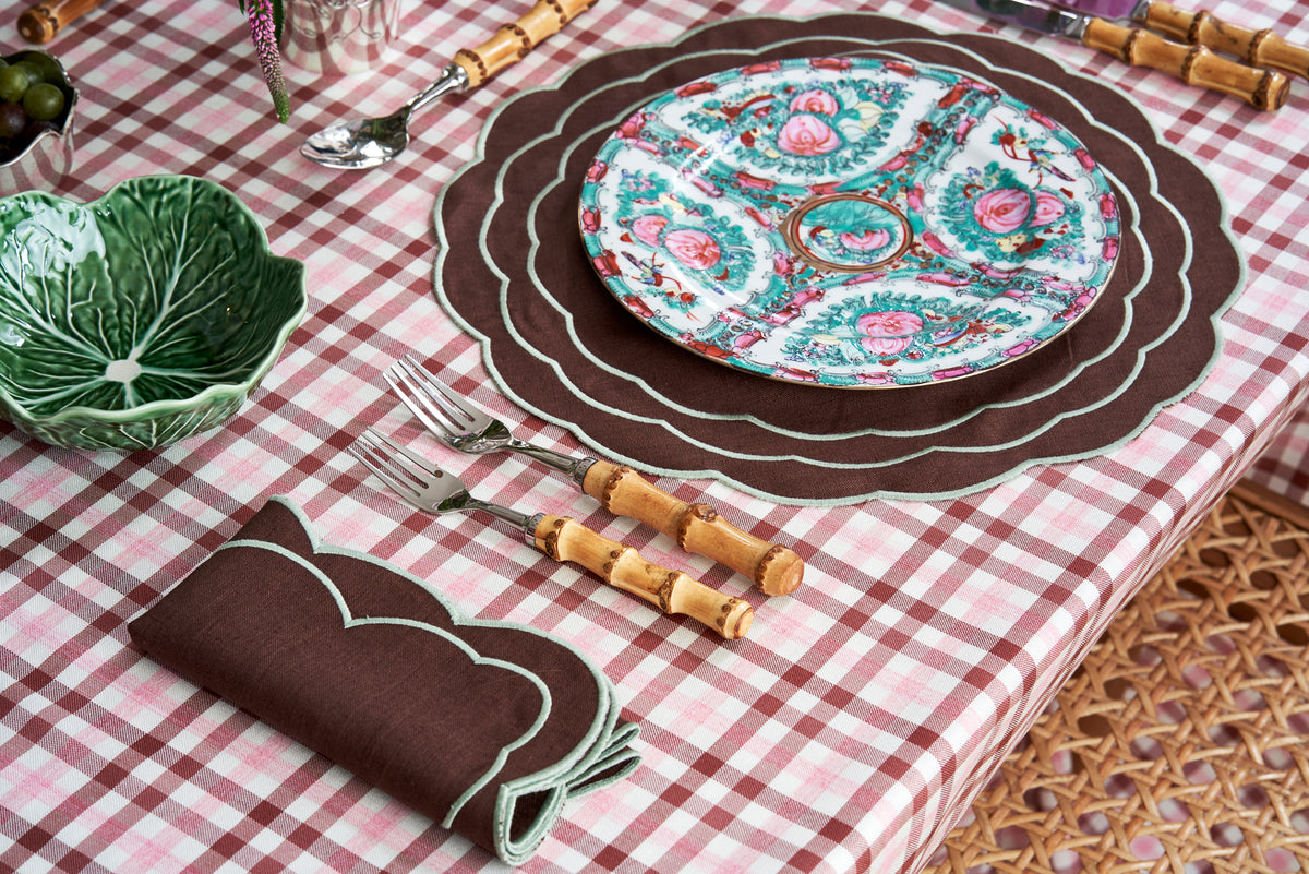 Overhead view of Sofia linen brown placemat showcasing fern green hand embroidery with a patterned table setting