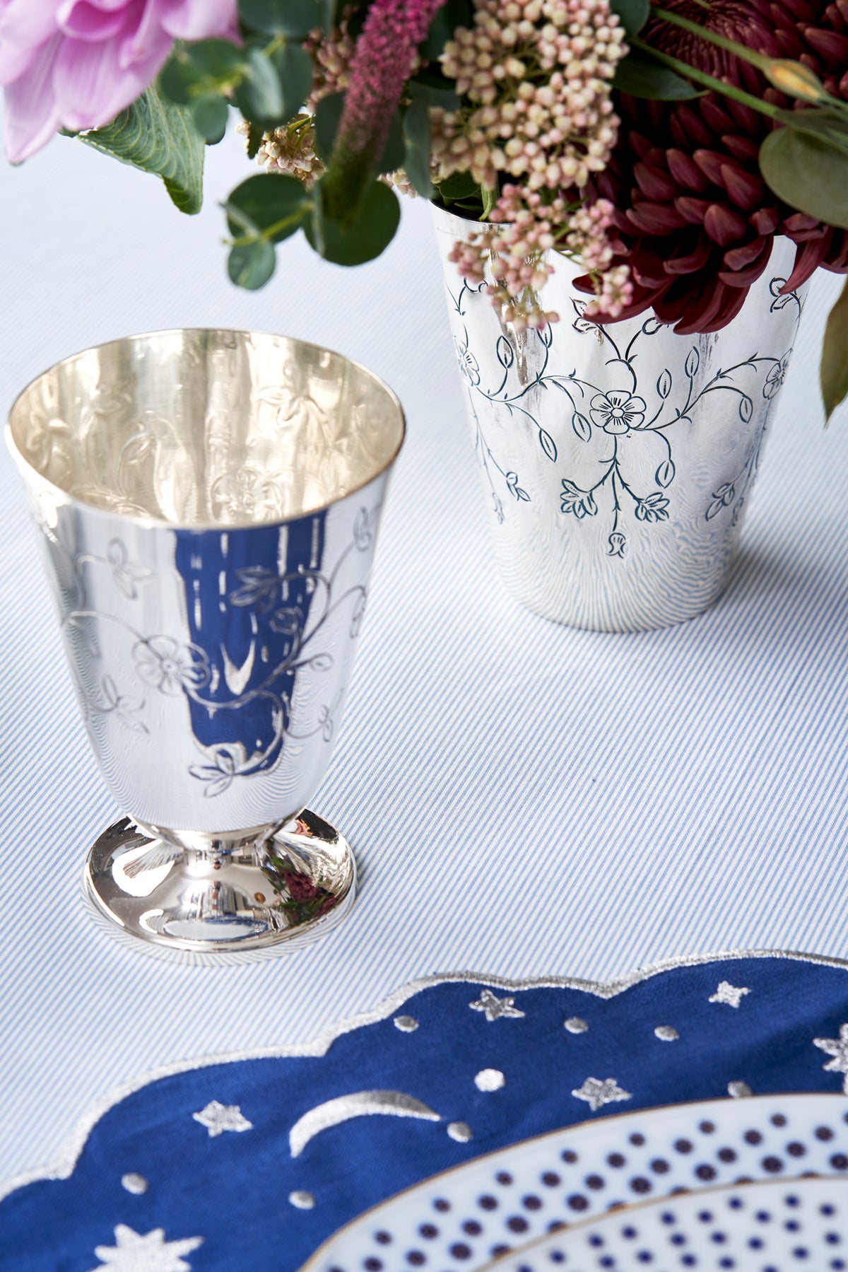 Front view of Lydia Cup showcasing molded and hammered sterling silver with flowers and table setting