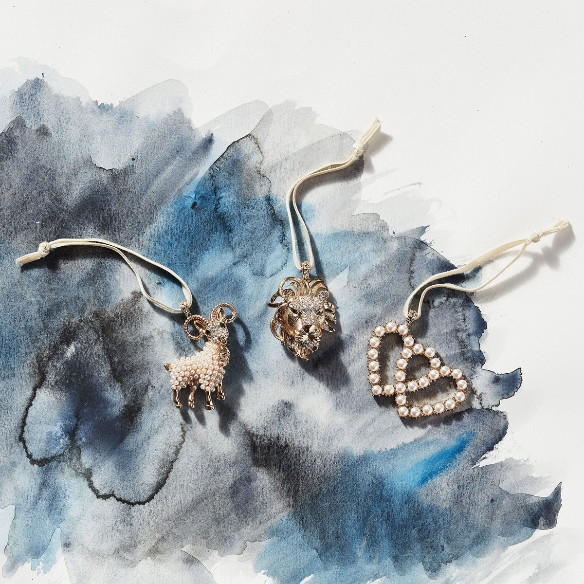 Close-up of Gemini Hanging Ornament with a pearl-covered twins symbol on a blue watercolor background