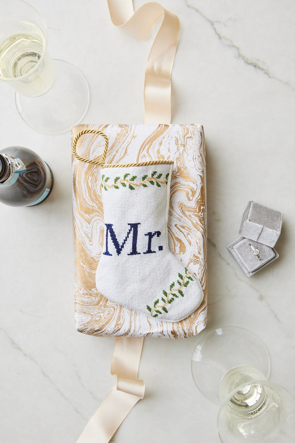 Top view of Mr. Bauble stocking showing white needlepoint with navy Mr lettering and green vine embroidery on marbled gift