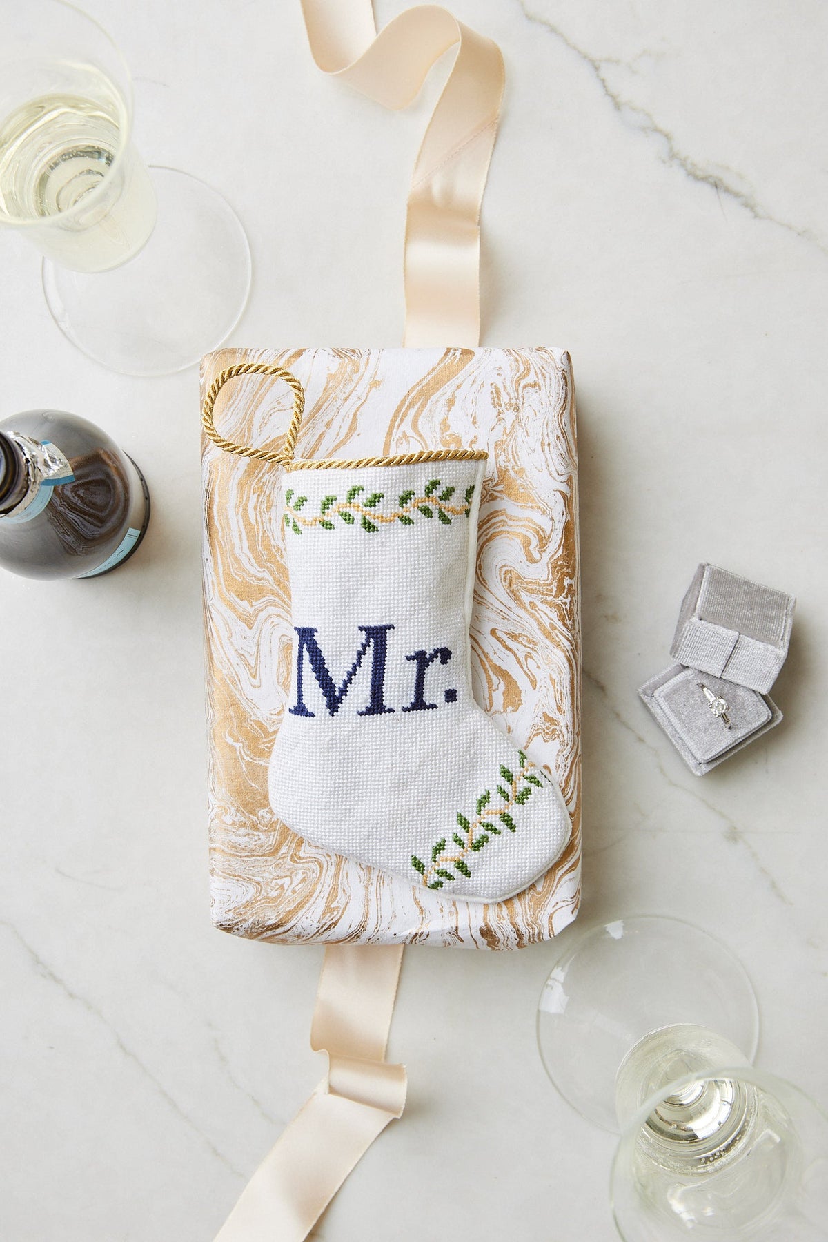Top view of Mr. Bauble stocking showing white needlepoint with navy Mr lettering and green vine embroidery on marbled gift