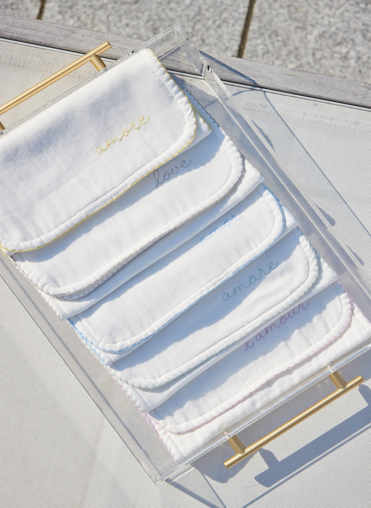 Top view of Love Languages Burp Cloth Set with five white cloths, pastel picot edges, and embroidered love in several languages