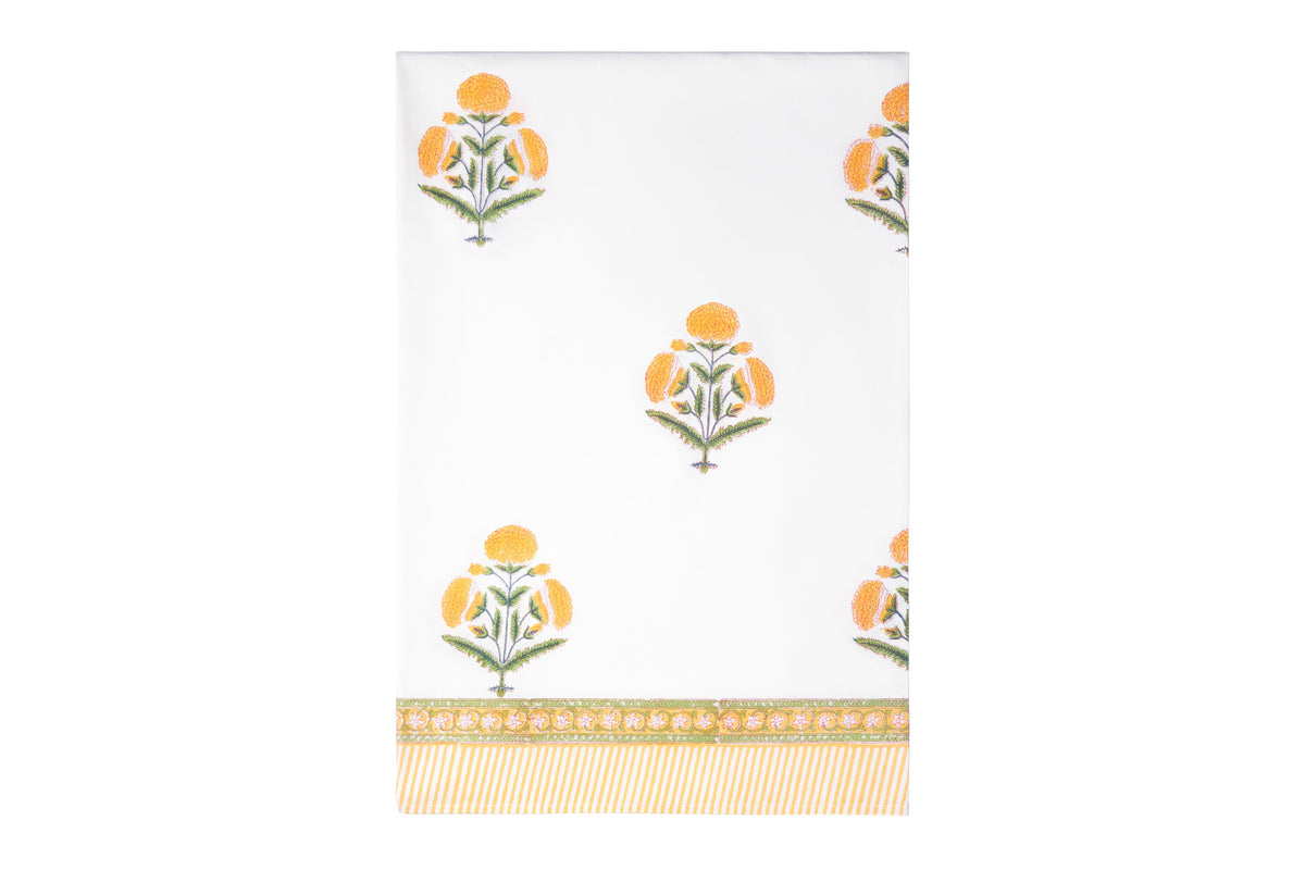 Flat lay of The Poppy Tablecloth showcasing vibrant yellow poppy flowers on white fabric with a patterned border