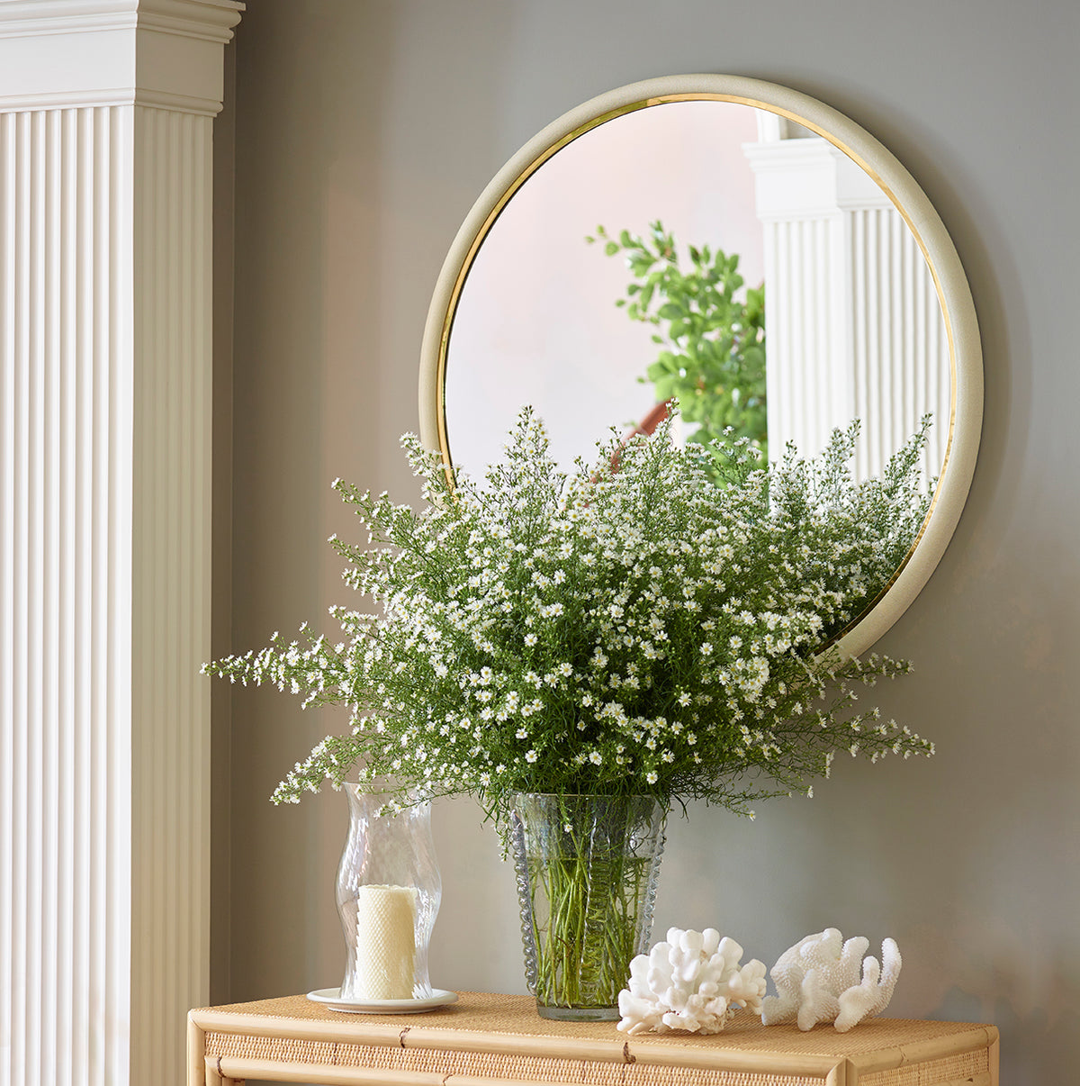 Front view of Shagreen Wall Mirror showcasing round cream shagreen frame with gold inner trim against a gray wall