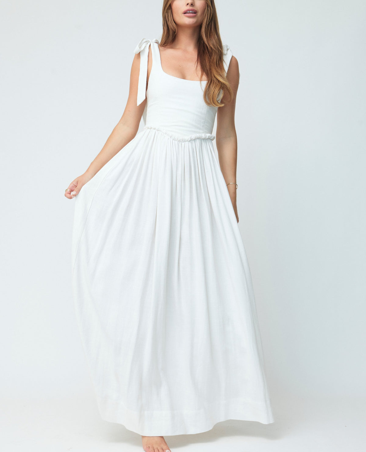 Front view of The Marie Dress in White showcasing a fitted white bodice and full gathered skirt on a pale gray studio background
