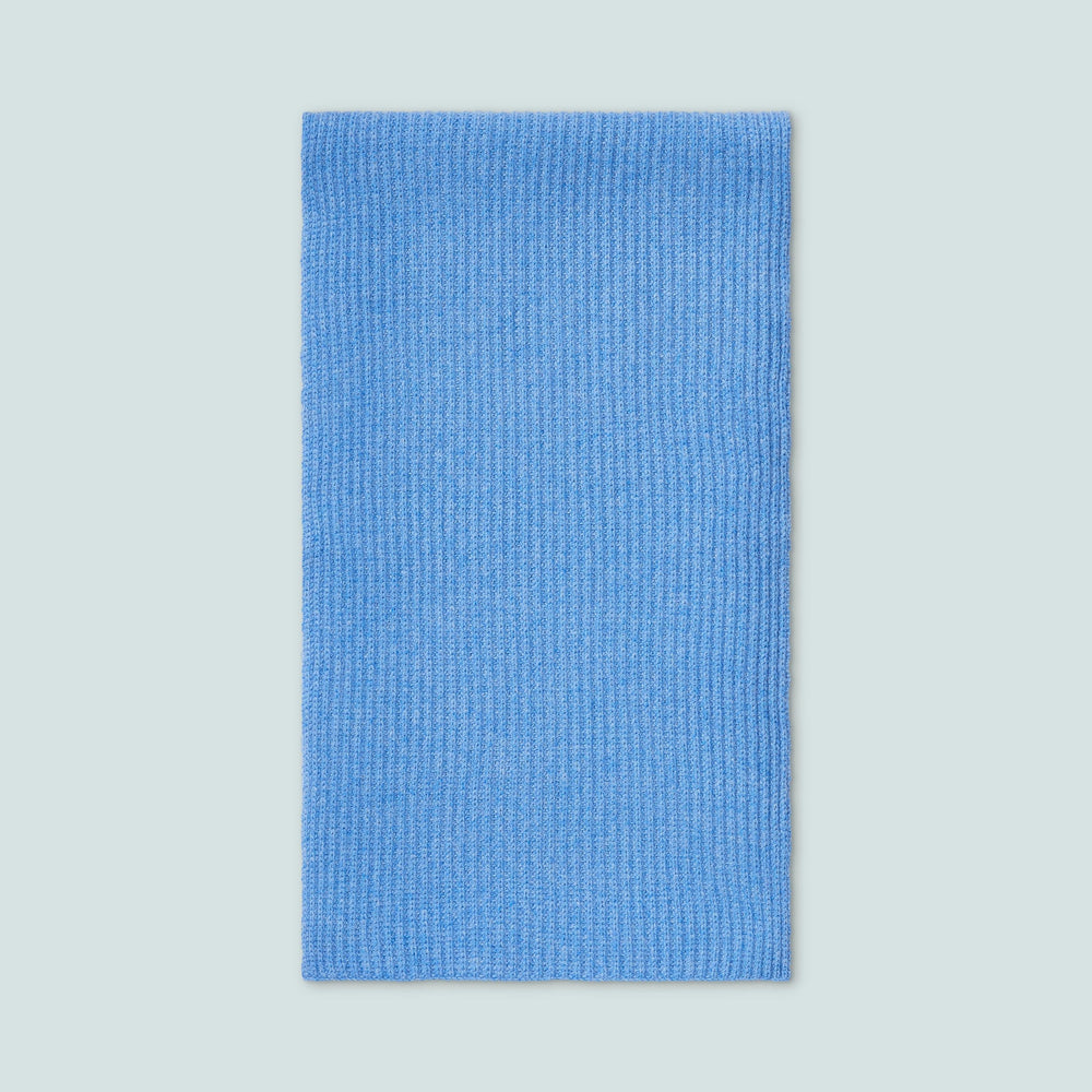 Flat-lay of blue cashmere scarf showing ribbed knit texture on pale blue background