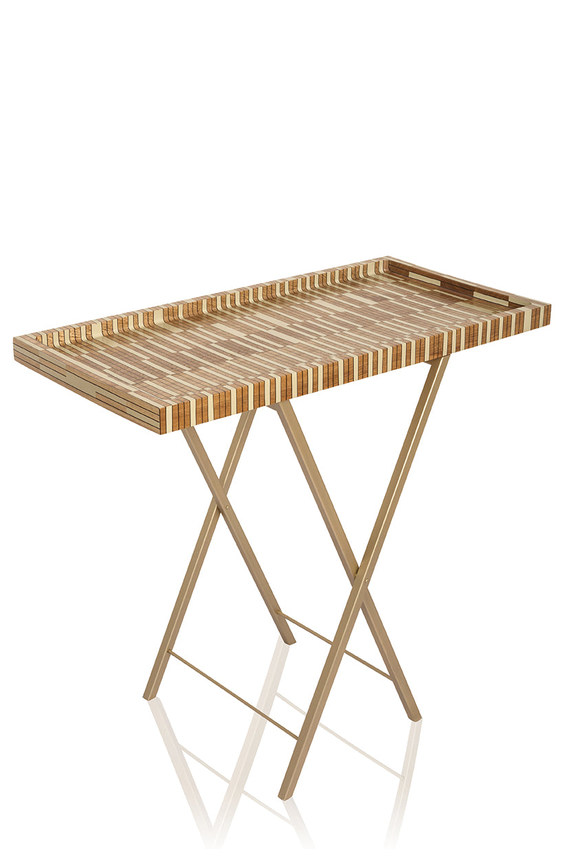 Angled view of bar tray and folding table showing striped oak tray with raised edges and gold X-frame legs