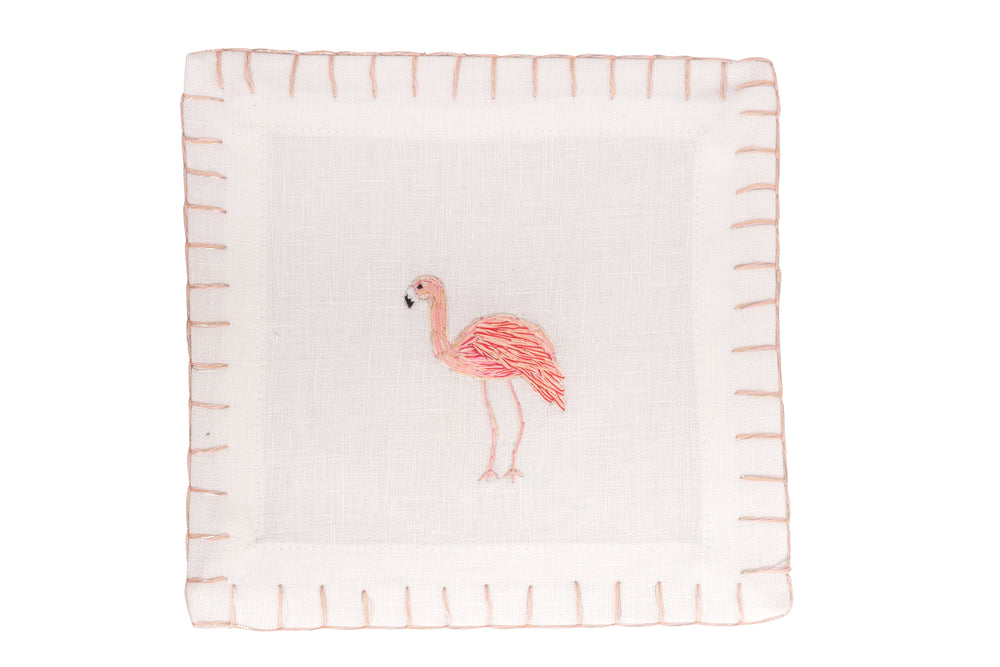 Top-down view of Flamingo cocktail napkin showcasing hand-embroidered pink flamingo and whipstitch border on white linen