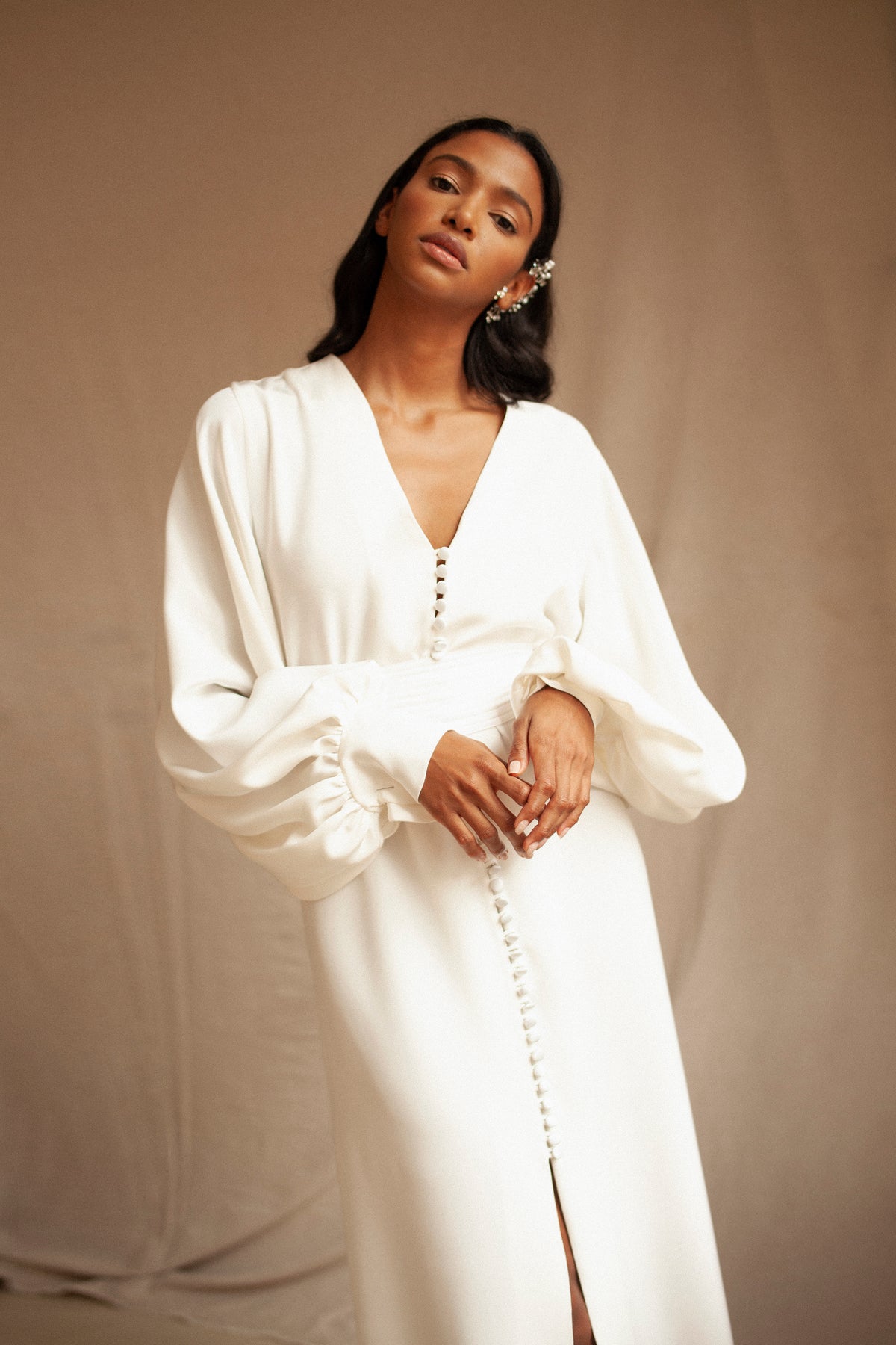 Front view of Afrodite Dress showcasing deep V-neck, covered button front, gathered voluminous sleeves and center slit