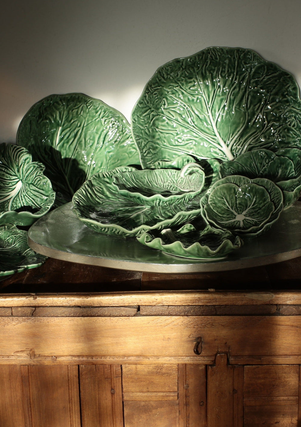 Front view of Cabbage oval platter 37.5 inch set of 2 showcasing embossed cabbage-leaf texture and glossy green glaze on a wooden surface