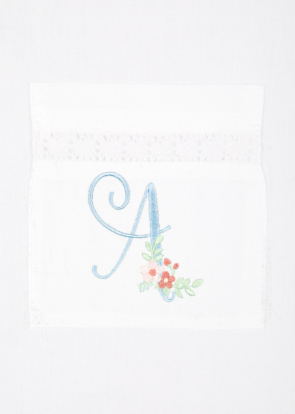 Close-up of Alison short-sleeve white cotton pajama pocket showcasing blue embroidered initial A with small pink and red flowers and lace trim