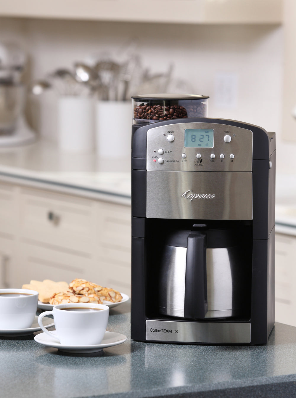 Front view of Capresso CoffeeTEAM TS with built-in grinder and stainless thermal carafe on counter with two coffee cups