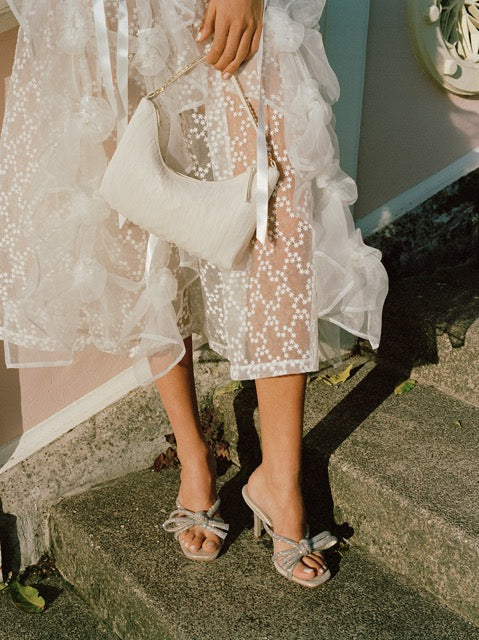Front view of Margi Mule in cappuccino suede with clear rhinestones on a model’s feet outdoors