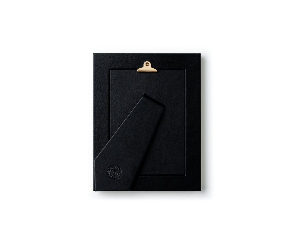 Back view of 5 x 7 picture frame in chestnut leather showcasing leather-wrapped easel and brass hanging clip on white