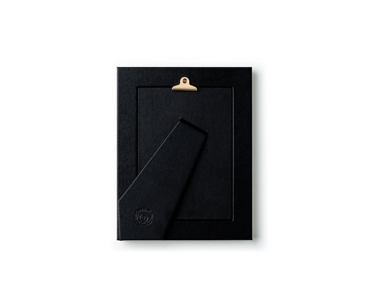 Back view of 5 x 7 picture frame in chestnut leather showcasing leather-wrapped easel and brass hanging clip on white