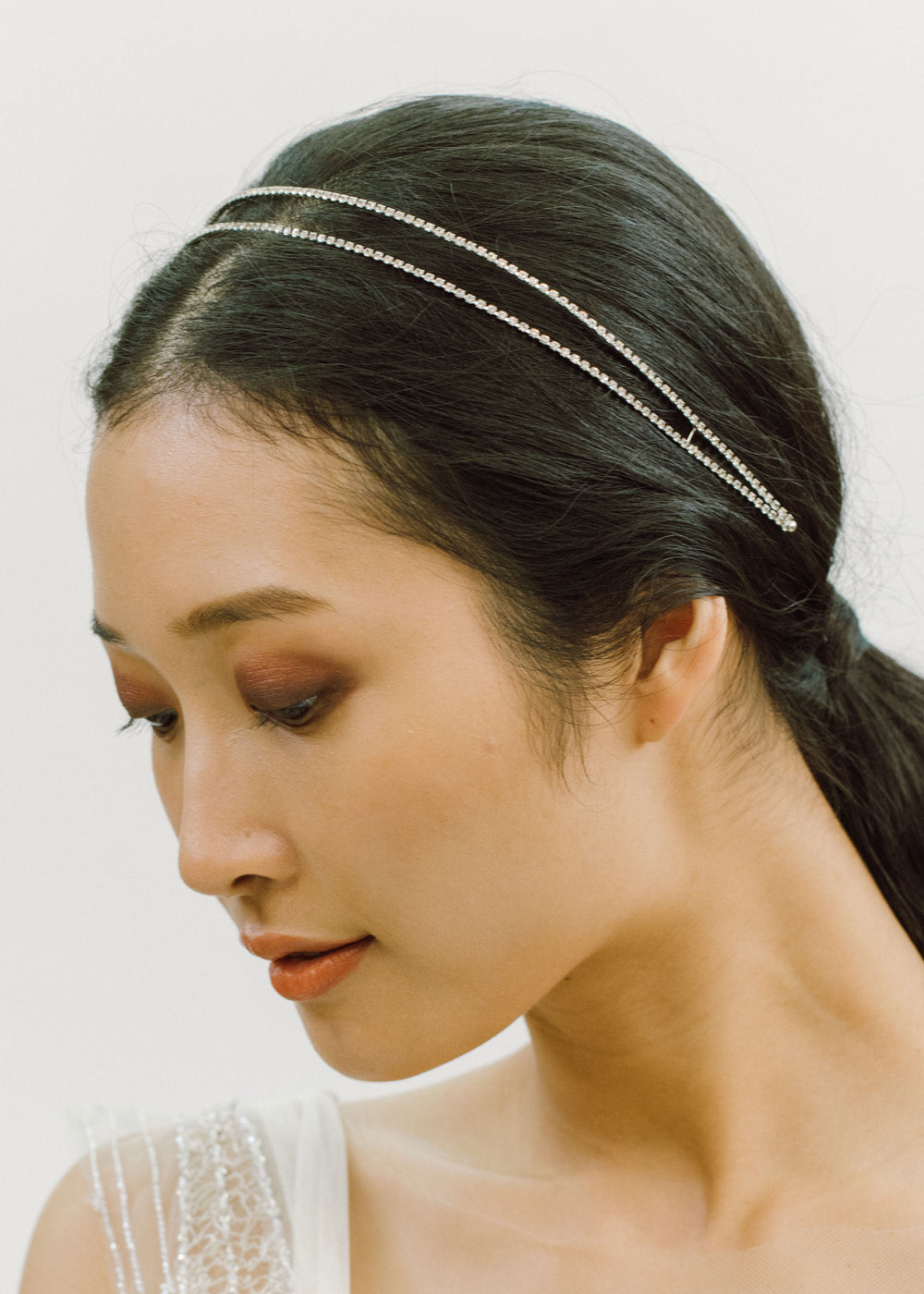 Side profile of Evie Headband showcasing dual rows of prong-set crystals on a model against a light background