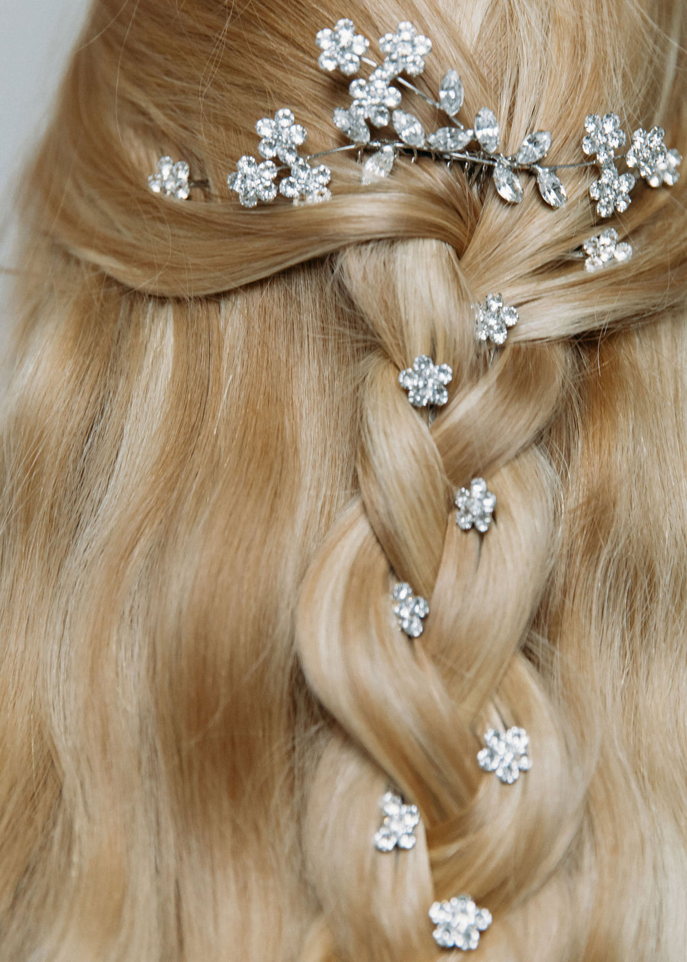 Close up of Violet Bobby Pin Set showcasing floral Swarovski crystal bobby pins woven into a blonde braided hairstyle