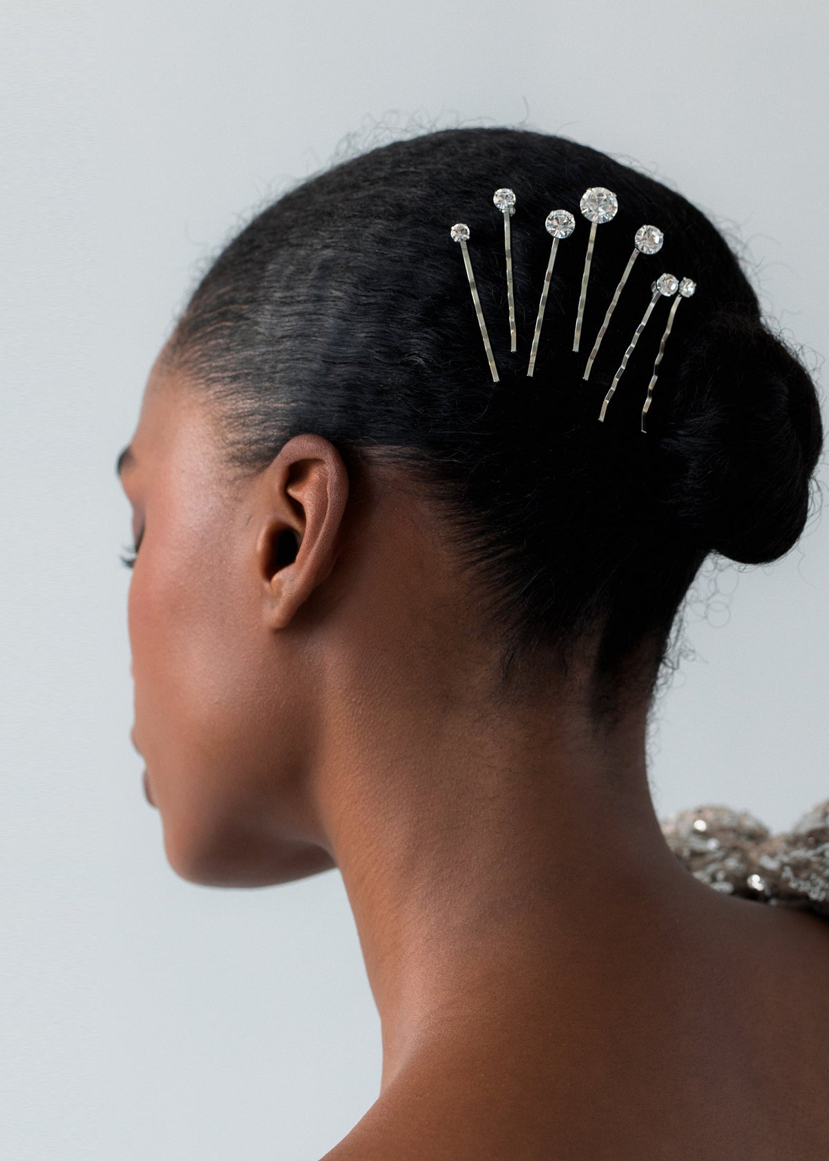 Side view of Misha Bobby Pins showcasing graduated Austrian crystals secured in dark hair with a neutral background