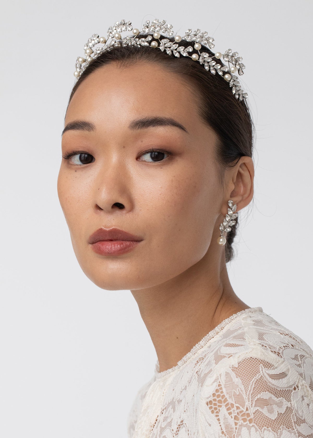 Close-up view of Delilah Tiara in Crystal showcasing crystal leaf sprays and pearls on a model against a light background