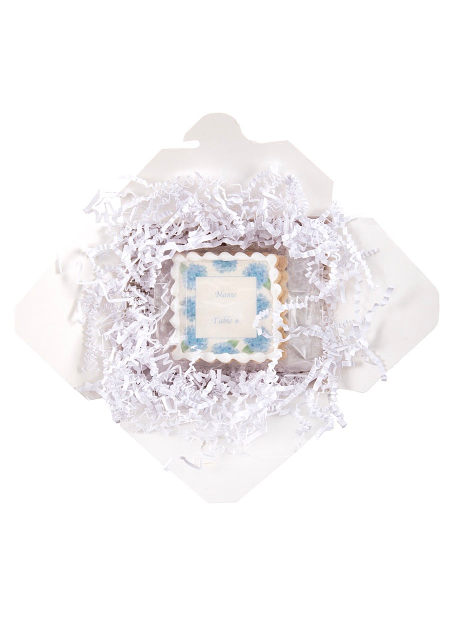 Top-down of Blue Hydrangeas name-plate sugar cookie with scalloped icing and editable name/table in a white gift box