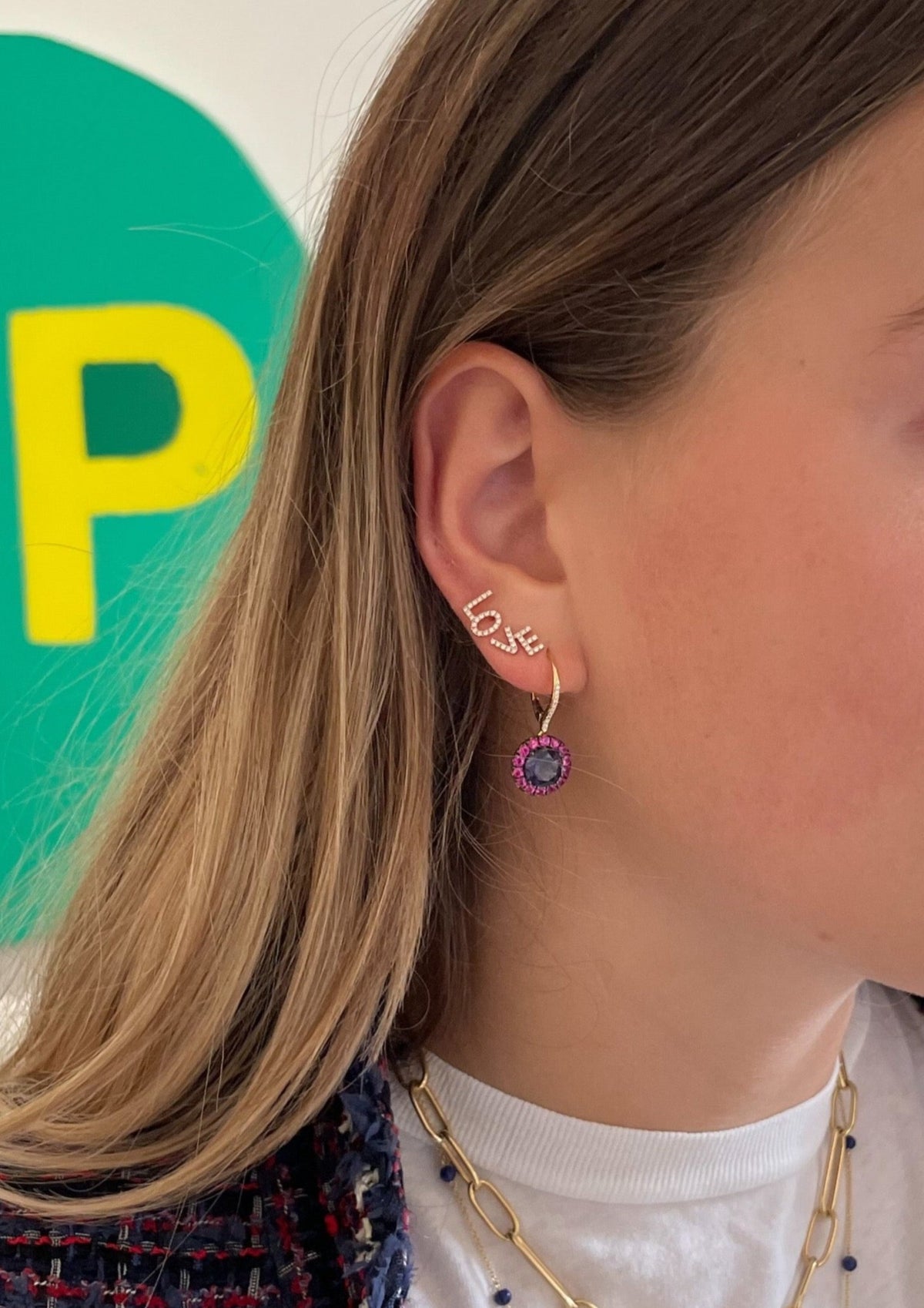 Side view of Gem Two Tone earring on model’s ear showing dark purple center gem with pink halo and two-tone metal
