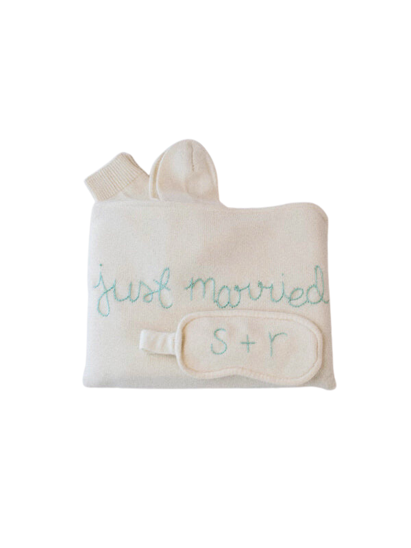 Folded cream cashmere travel set with just married embroidery, socks, and monogrammed eye mask SR on white background