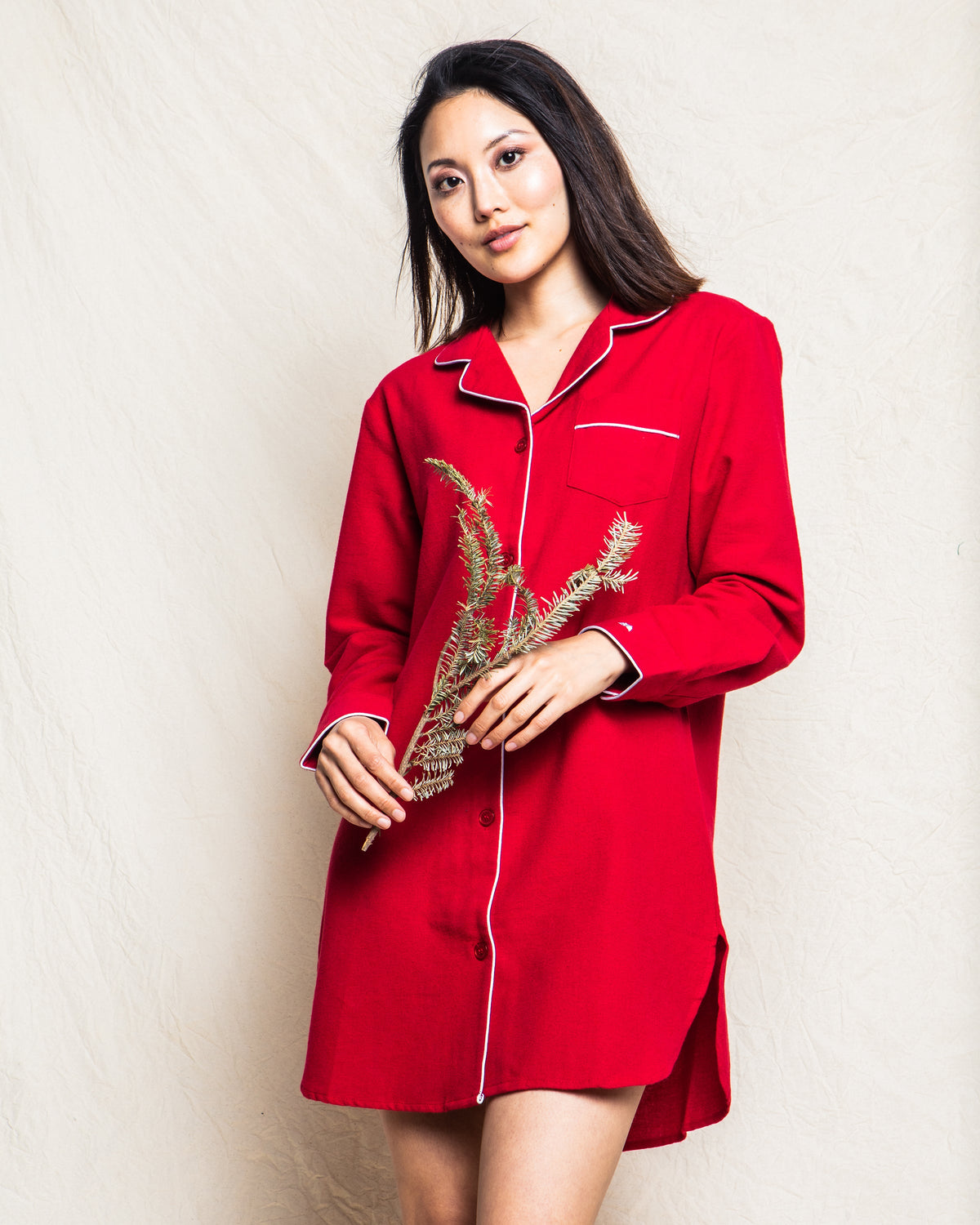 Front view of women’s red flannel nightshirt showcasing white piping, button-front and chest pocket on a neutral backdrop