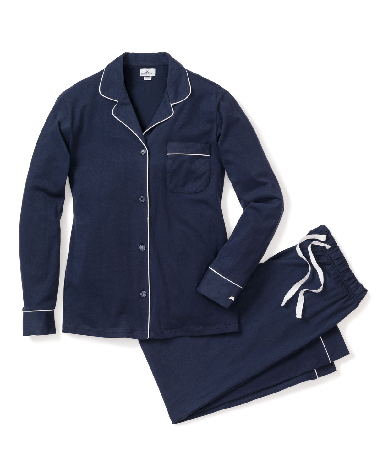 Flat lay of women’s navy flannel pajama set with white piping, button-front top and drawstring pants on white background