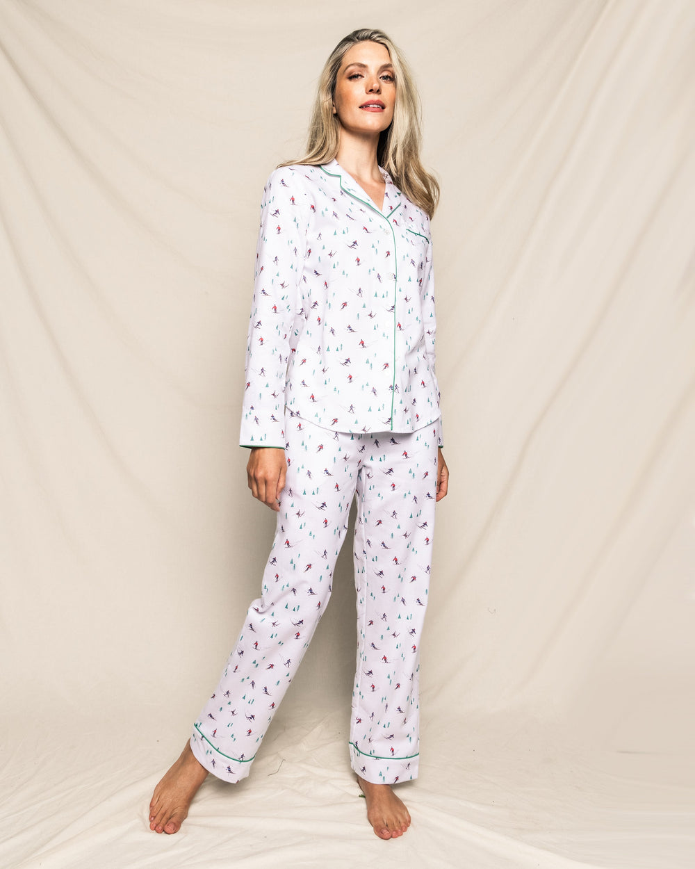 Front view of Women’s Après Ski pajama set showcasing white cotton top and pants with skier and tree print and green piping, modeled