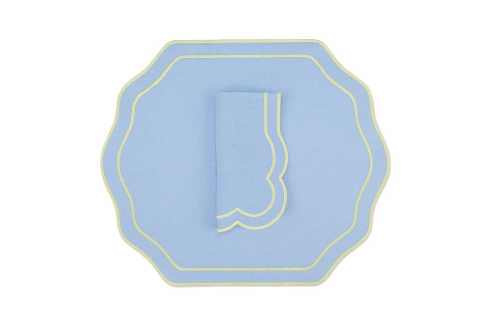 Top-down view of Stucco linen placemat and folded napkin in air blue with yellow scalloped trim on white background