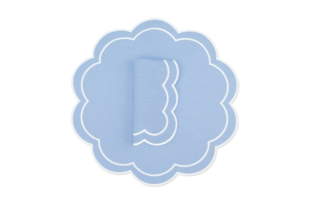 Top view of Bloom linen napkin and scalloped placemat set of 4 in air blue with white double-stitching on white background