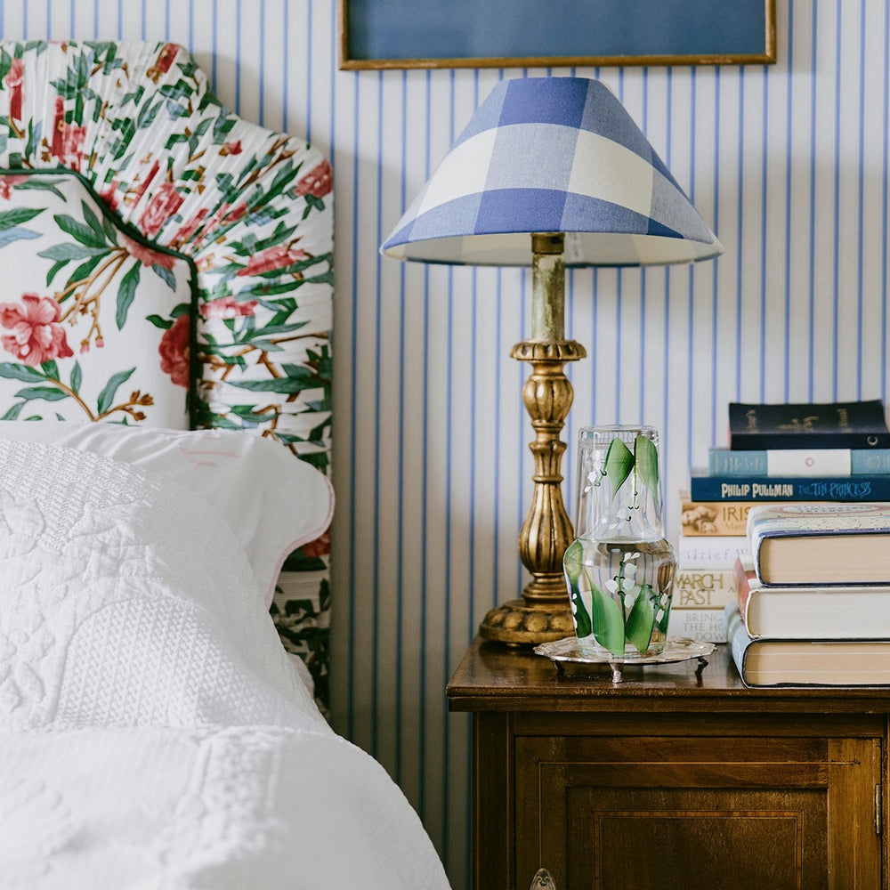 Lily of the Valley carafe and tumbler showing hand-painted floral design on bedside table with lamp and books