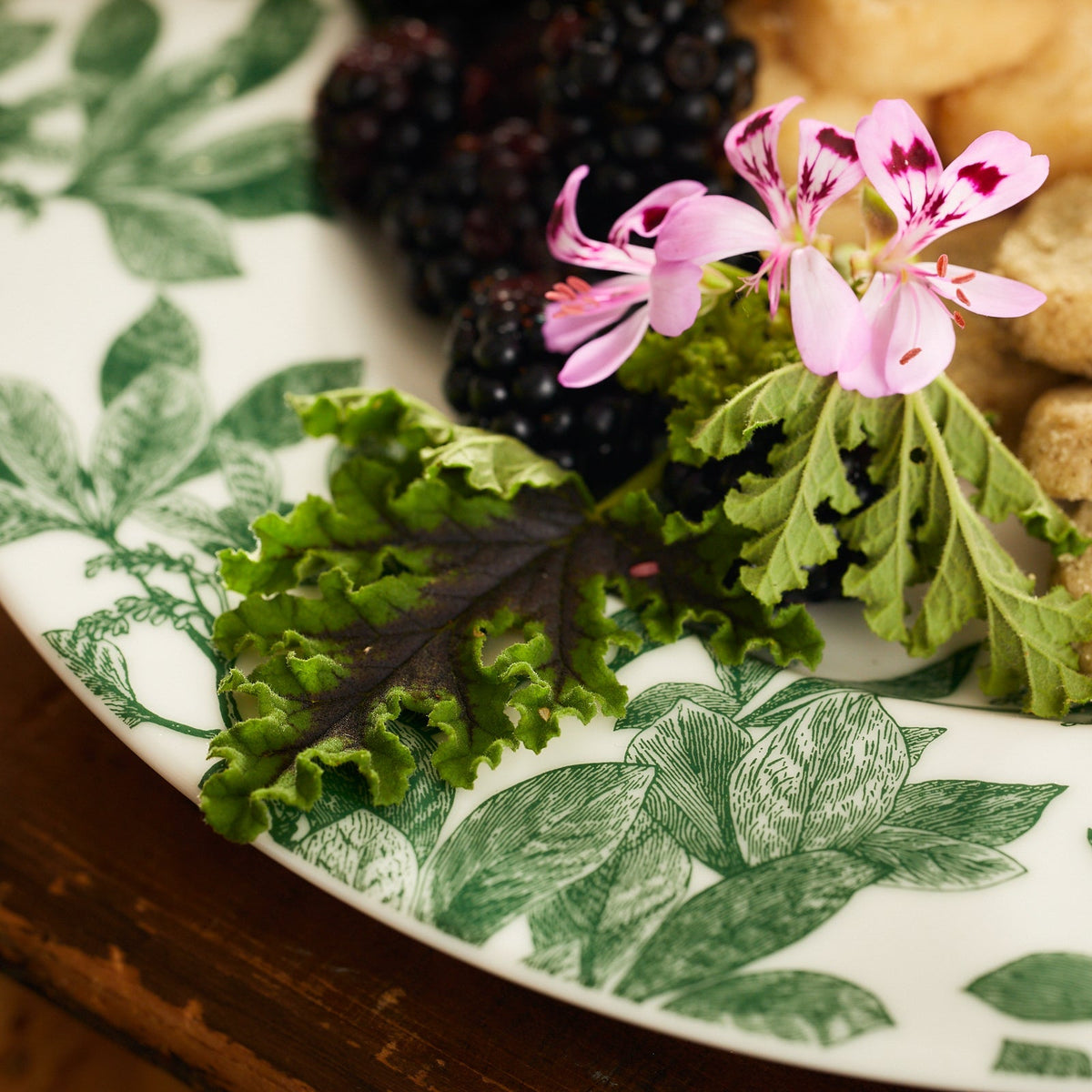 A vintage Arbor Green Dinner Plate by Caskata with green berries and a flower on it.