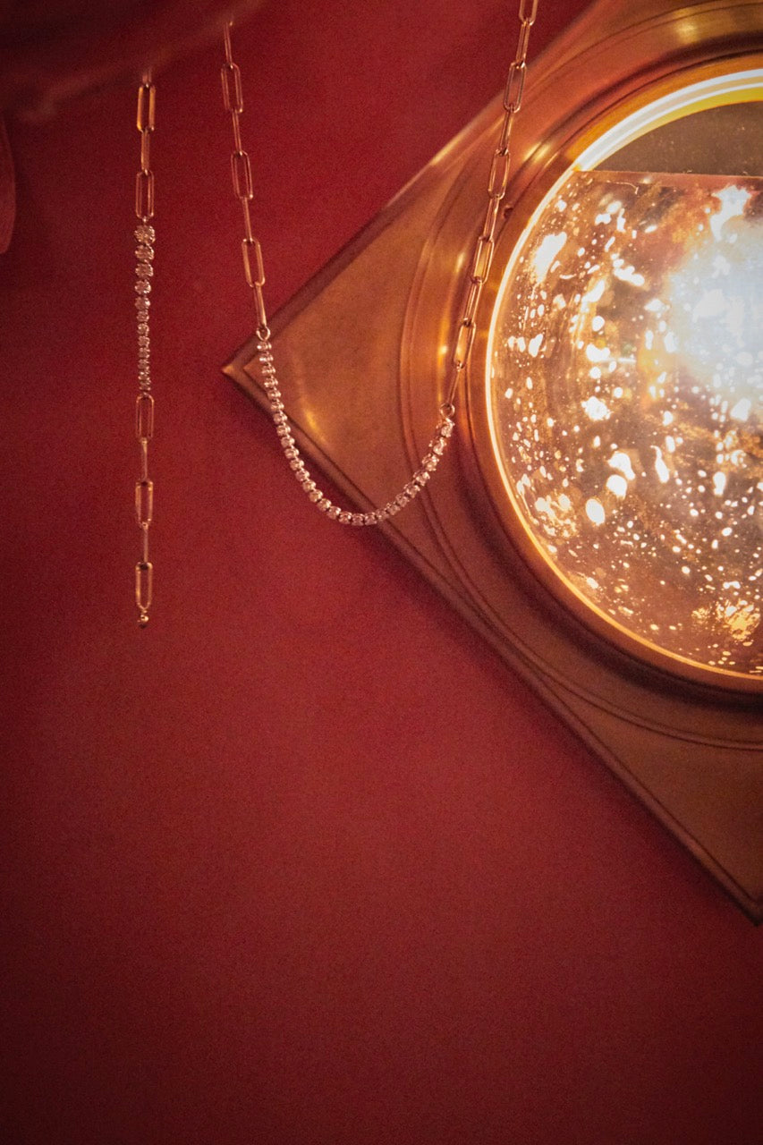 Close view of gold ascending diamonds on chain tennis bracelet showcasing rectangular links with a red backdrop