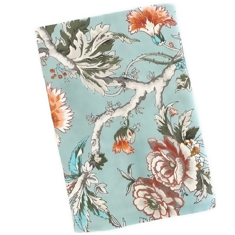 Teal blue tablecloth with gray and white branches, orange and wine flowers and green leaves