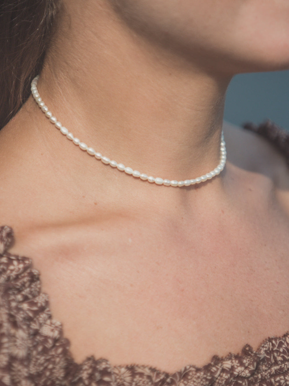 Close-up of Bella Necklace choker showcasing small white freshwater pearls on a model’s neck