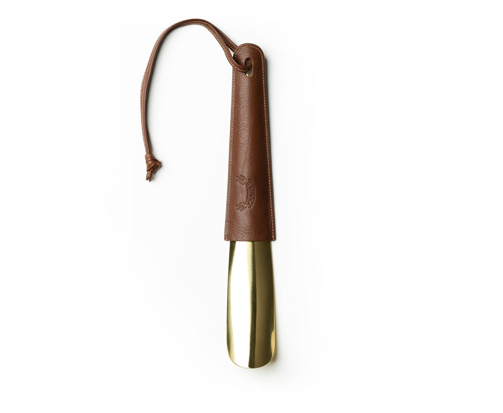 Front view of Brass-Tipped Shoehorn No. 239 showcasing brass tip and vintage chestnut leather sleeve with wrist strap on white background