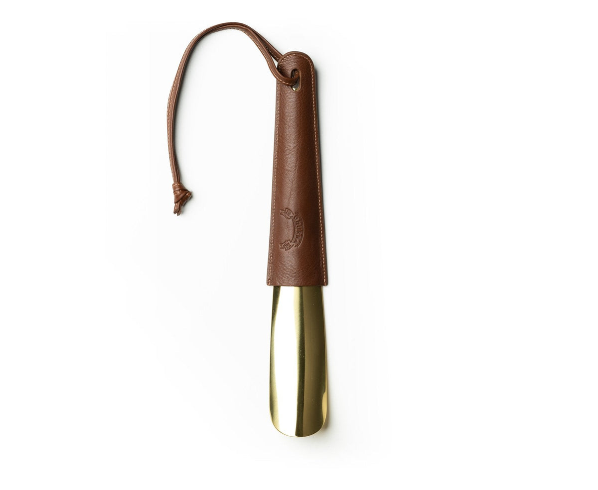 Front view of Brass-Tipped Shoehorn No. 239 showcasing brass tip and vintage chestnut leather sleeve with wrist strap on white background
