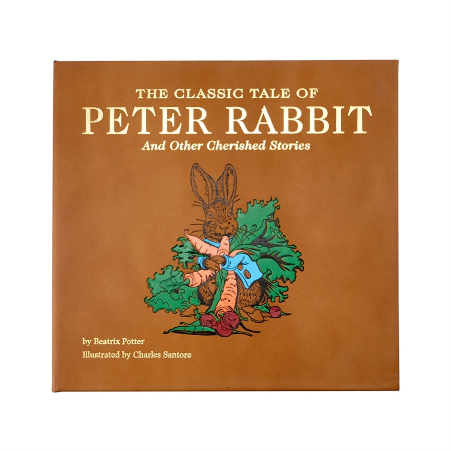 Front view of The Classic Tale of Peter Rabbit bonded leather book showing tan cover with illustrated rabbit holding carrots
