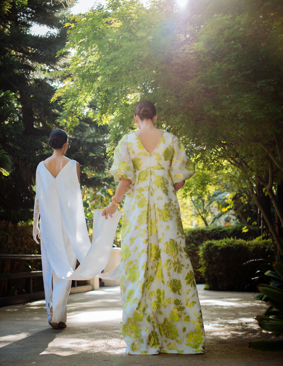 Back view of Full Sleeve Pleat Front Gown in pistachio floral showing puff sleeves and pleated front in sunlit garden