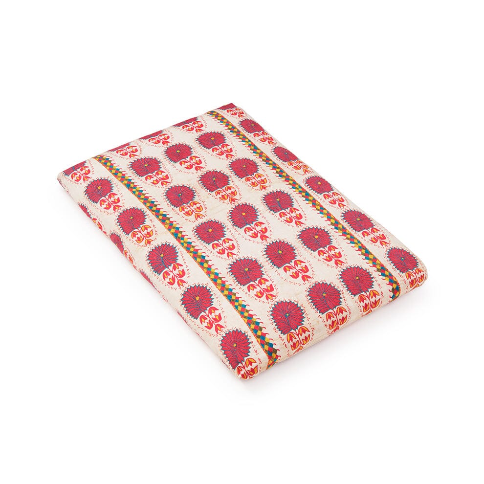 Angled view of folded Fuchsia Daisy Suzani fitted crib sheet showcasing fuchsia daisy Suzani floral print on white background