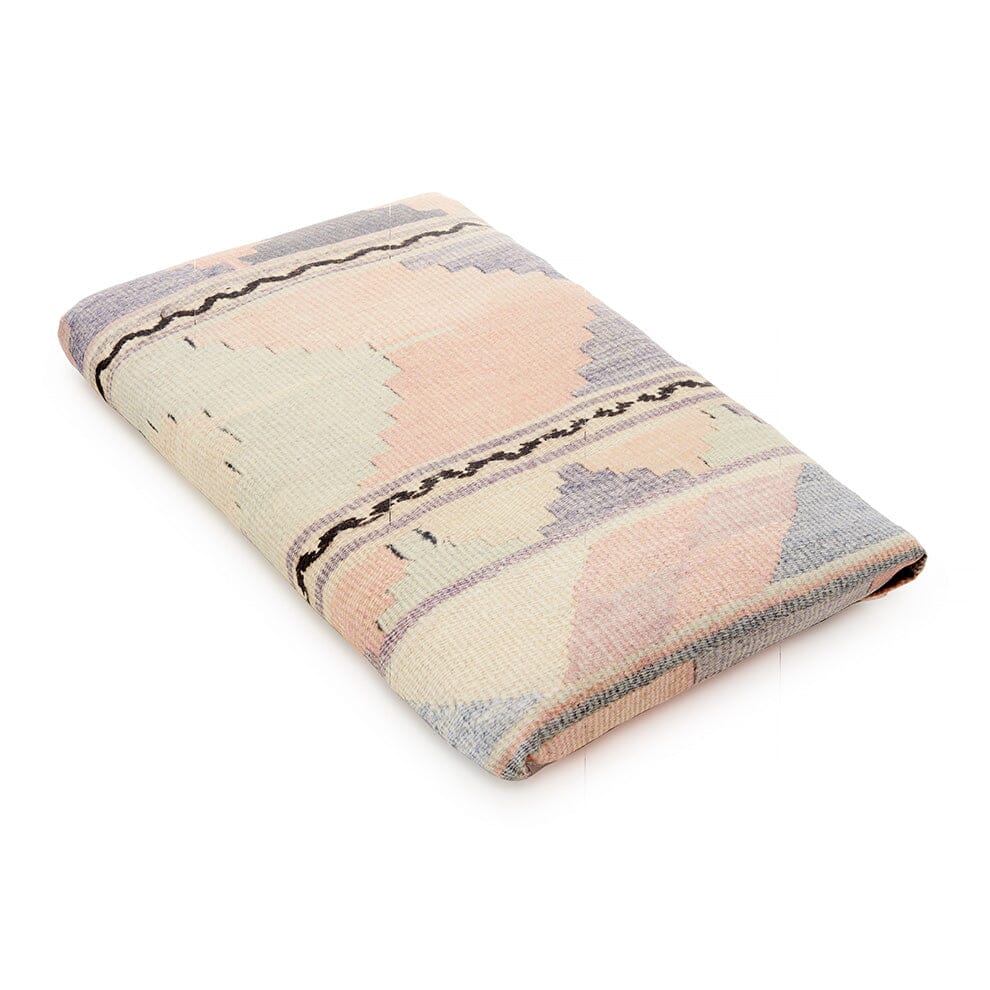 Angled view of the Light Shell Psychedelic Kilim Crib Sheet showcasing its pastel geometric kilim pattern on a white background