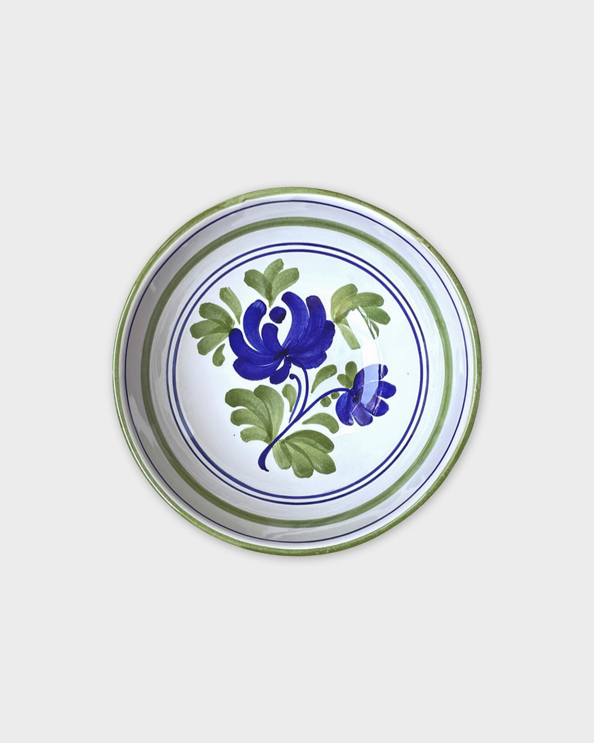 Top view of Blossom Bowl in Blue showcasing hand-painted blue floral motifs and green rim on a white background