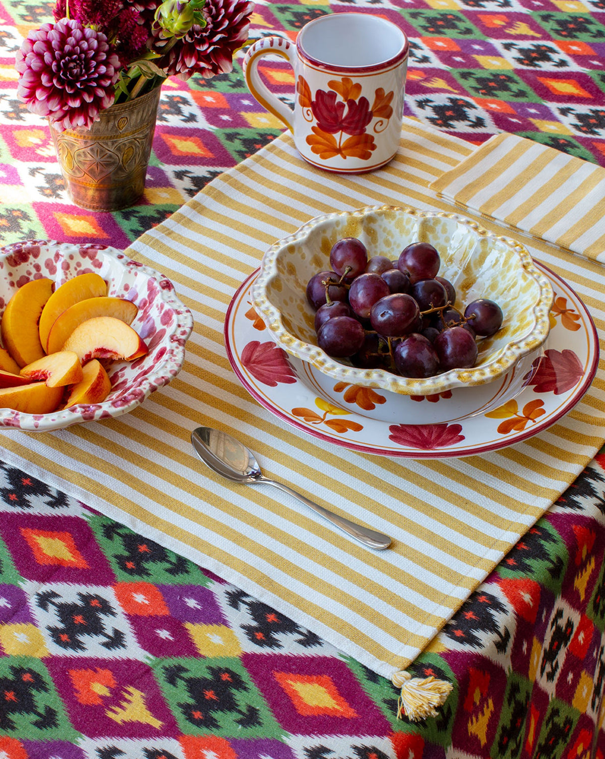 Front view of Blossom Mug in Yellow showcasing hand-painted floral motifs with a colorful table setting