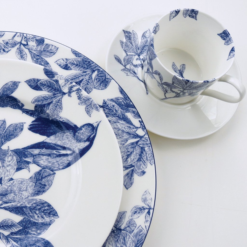 Close-up of Blue Arbor Cup & Saucer showcasing hand-drawn blue leafy branches on creamy white porcelain against a white background