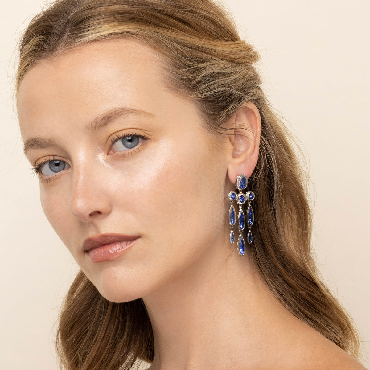 Right close-up of L&H Bride Long Girandole earrings with cascading midnight-blue pear-shaped stones on model